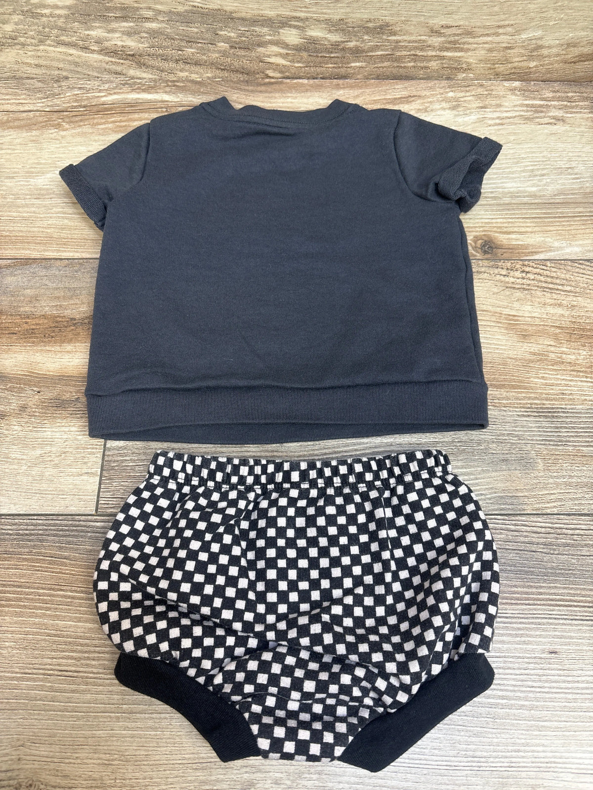 Top view of Cat & Jack two-piece shirt and bloomers set showing a dark gray shirt and checkerboard bloomers on a wood surface