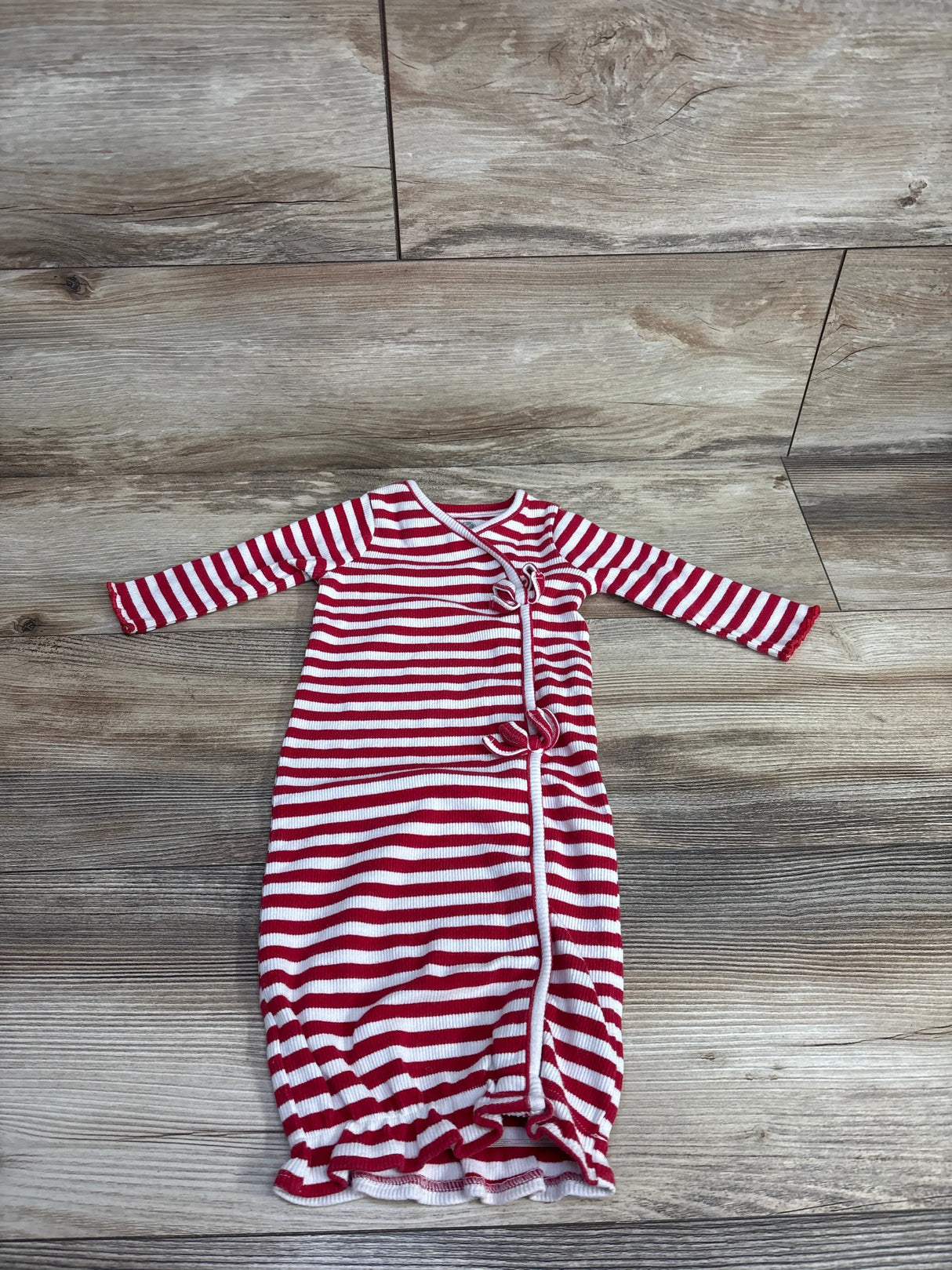 Red and white striped baby gown with long sleeves on wood background