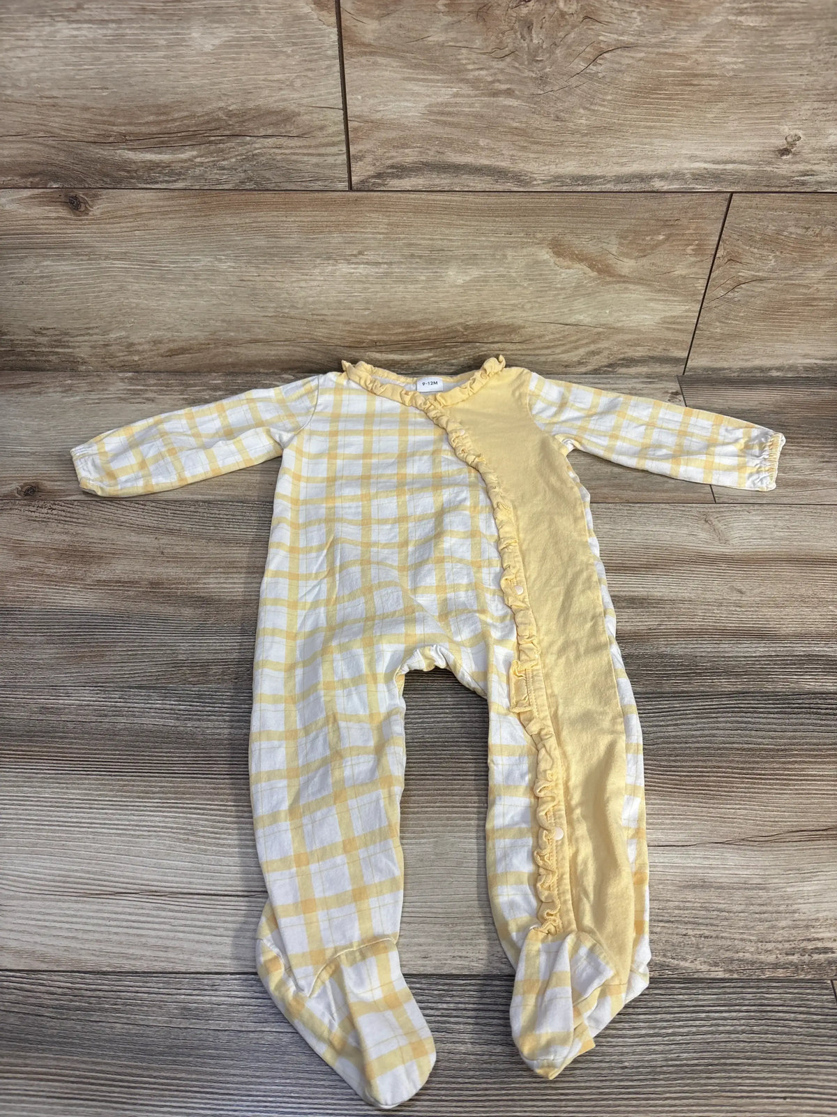 Flat lay of yellow and white plaid ruffle sleeper showcasing side snaps and long sleeves on a wood-grain background