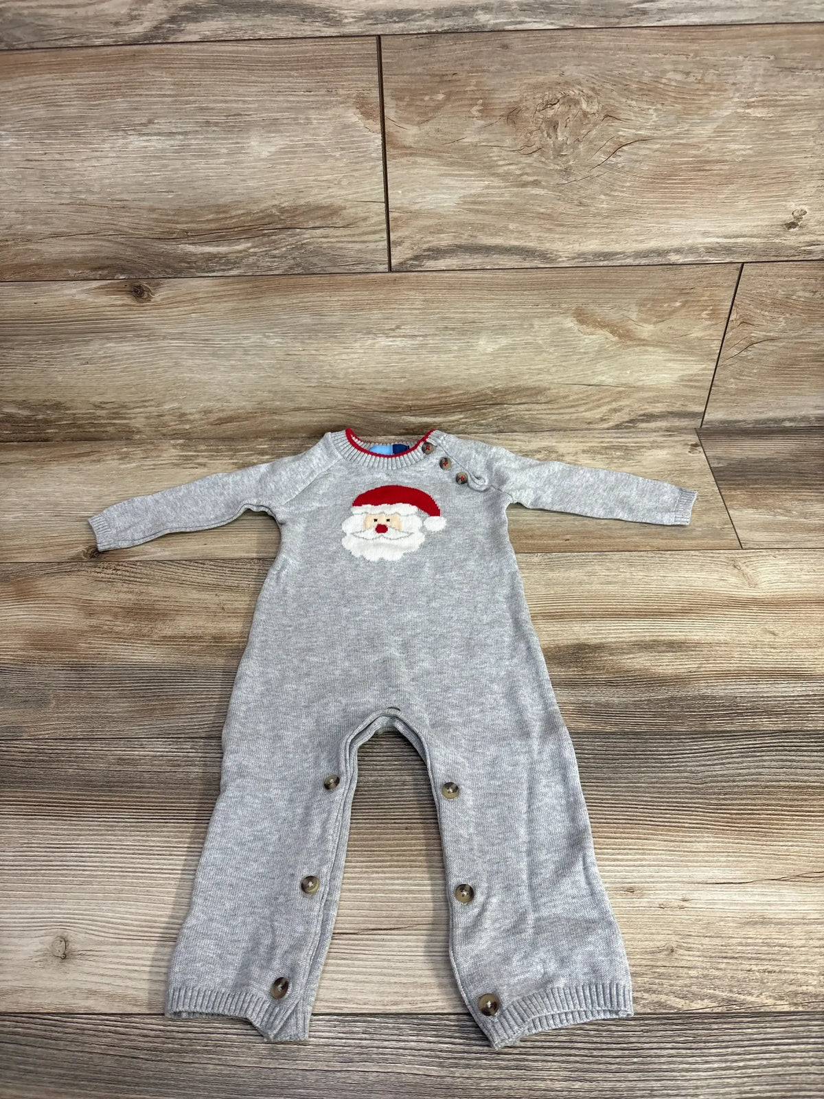 Gray baby onesie with Santa graphic, long sleeves, and snap buttons on wood floor
