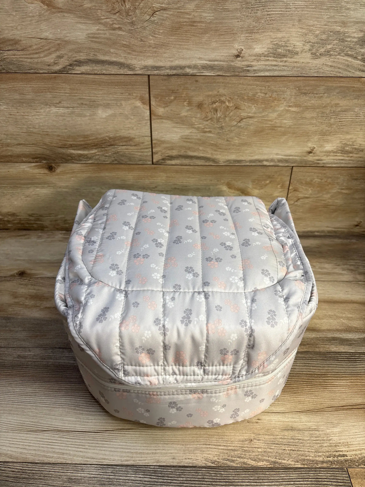 Front view of Baby Delight Snuggle Nest Harmony Portable Infant Lounger showcasing its gray floral pattern and raised sides on a wood surface