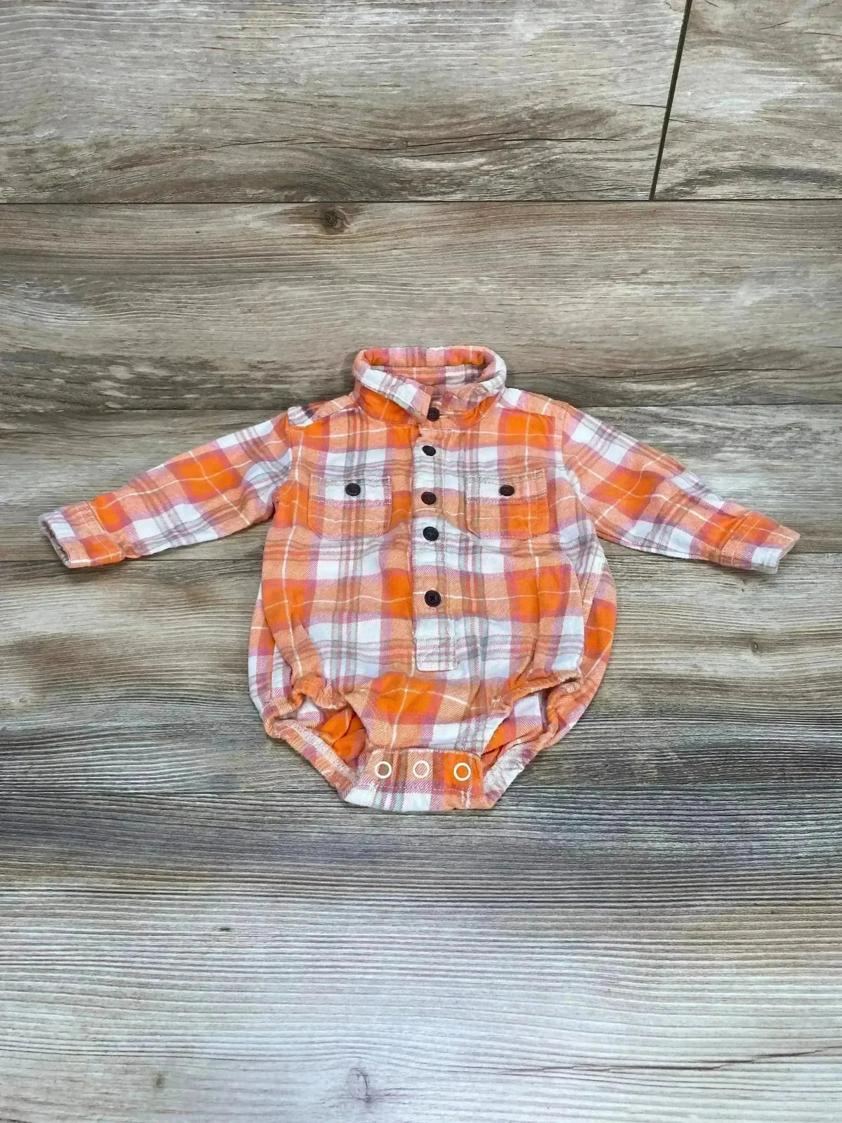 Front view of Oshkosh orange plaid flannel button-up bodysuit showing button-front and snap bottom on white