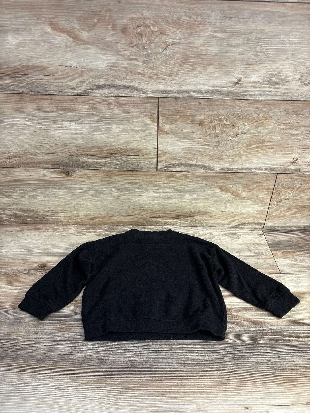 Back flat lay of Zara crewneck sweatshirt 9-12 months in black showing long sleeves and ribbed cuffs on wood floor