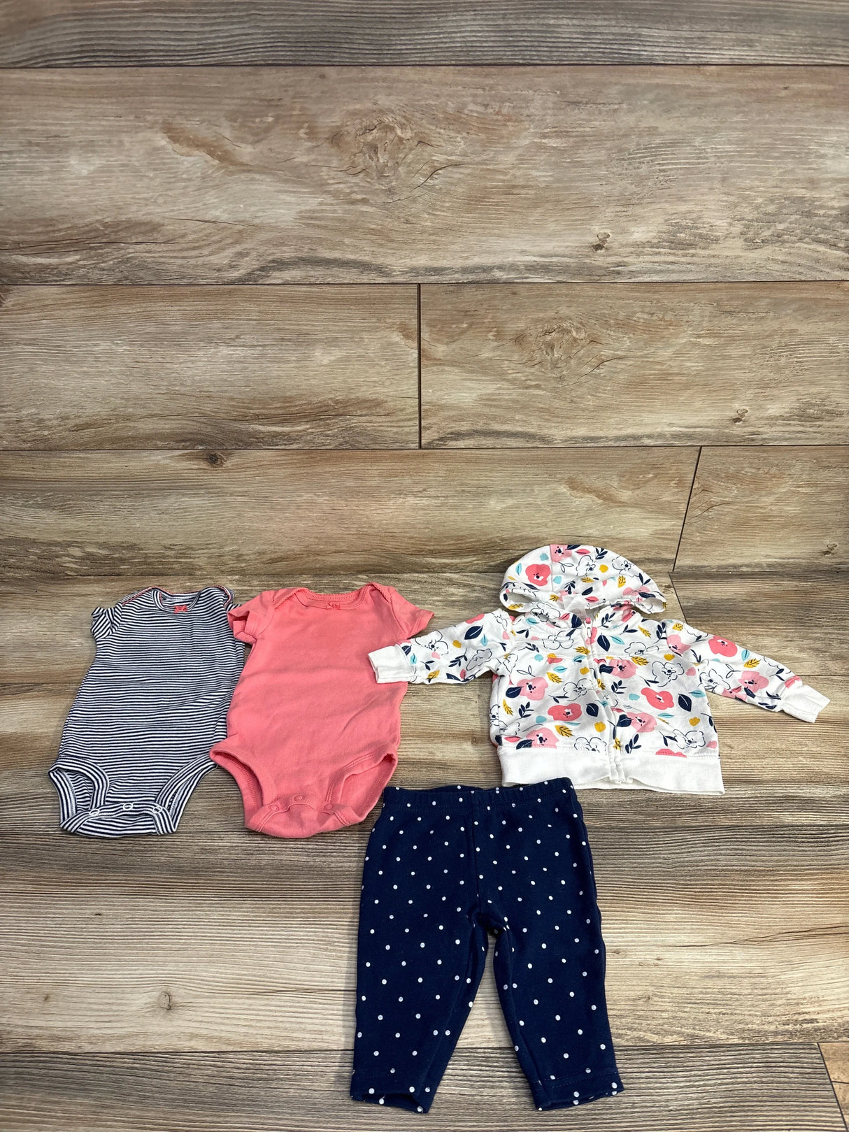 Top view of Simple Joys 4-piece newborn (0-3M) floral zip jacket set: two onesies, floral hoodie, navy polka-dot pants