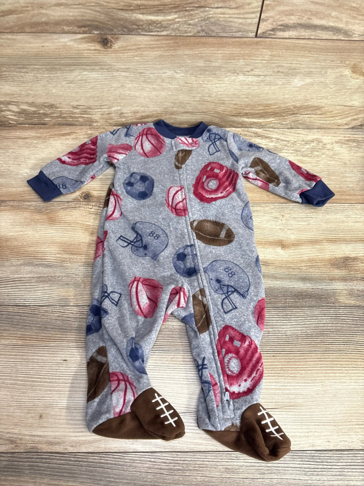 Gray baby fleece sleeper with blue cuffs and football, basketball, soccer ball, and glove prints, footed with football stitch design