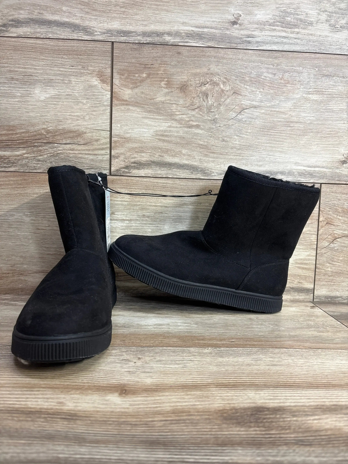 Black suede kids winter boots with rubber soles on wood floor background