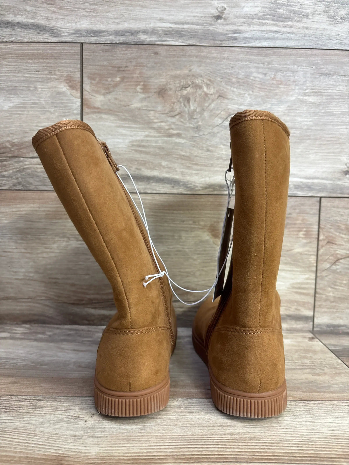 Pair of brown suede children's boots with side zippers on wooden floor