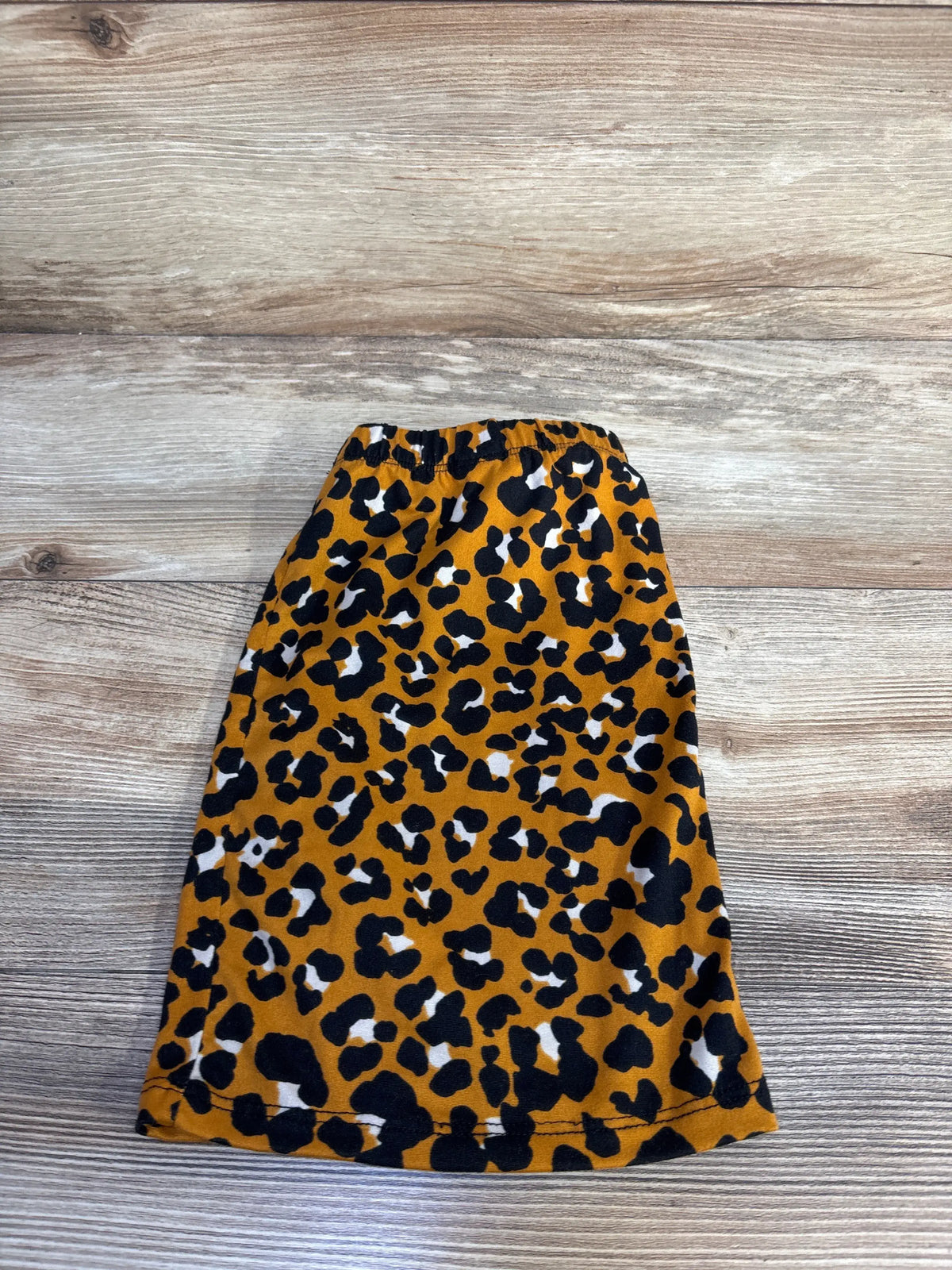 Front view of Little Loper’s brown leopard print skirt, size 18-24 months, showcasing elastic waistband on wood surface