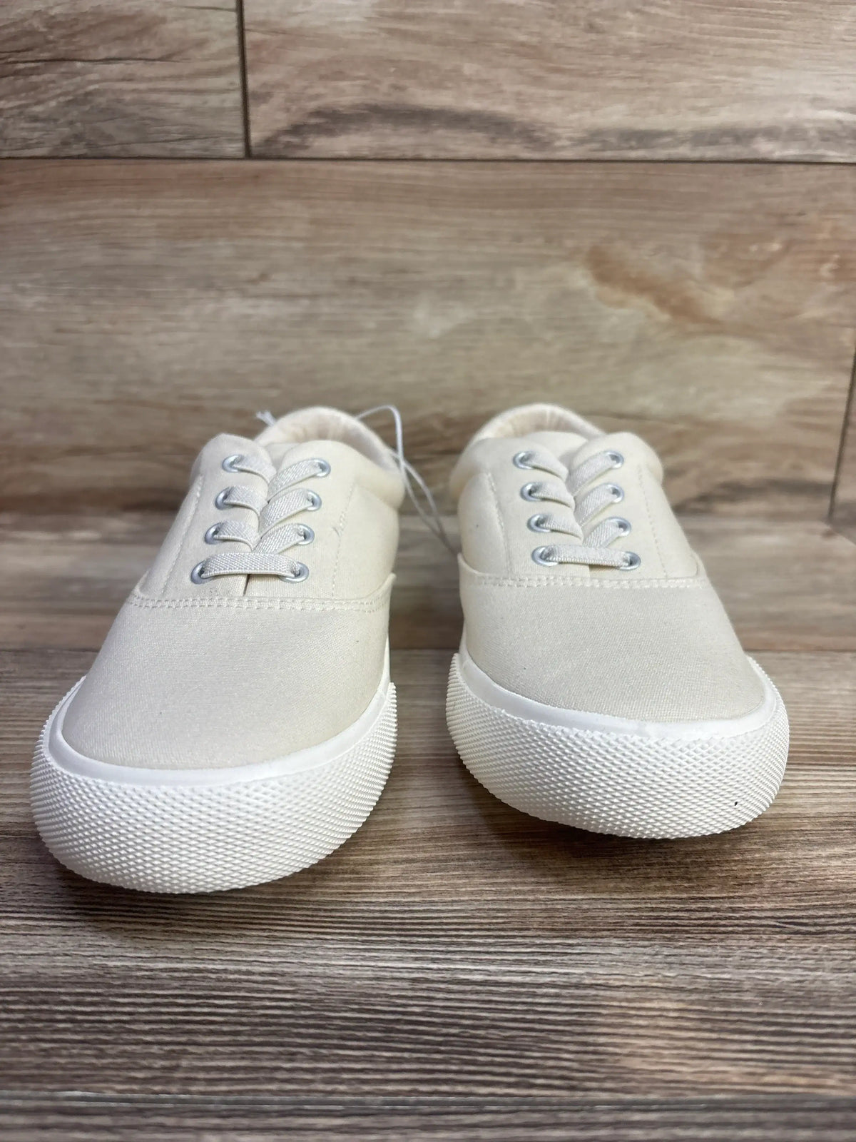 Front view of Cat and Jack Tyler slip-on sneakers showing off-white canvas, elastic laces, white rubber soles on wood floor