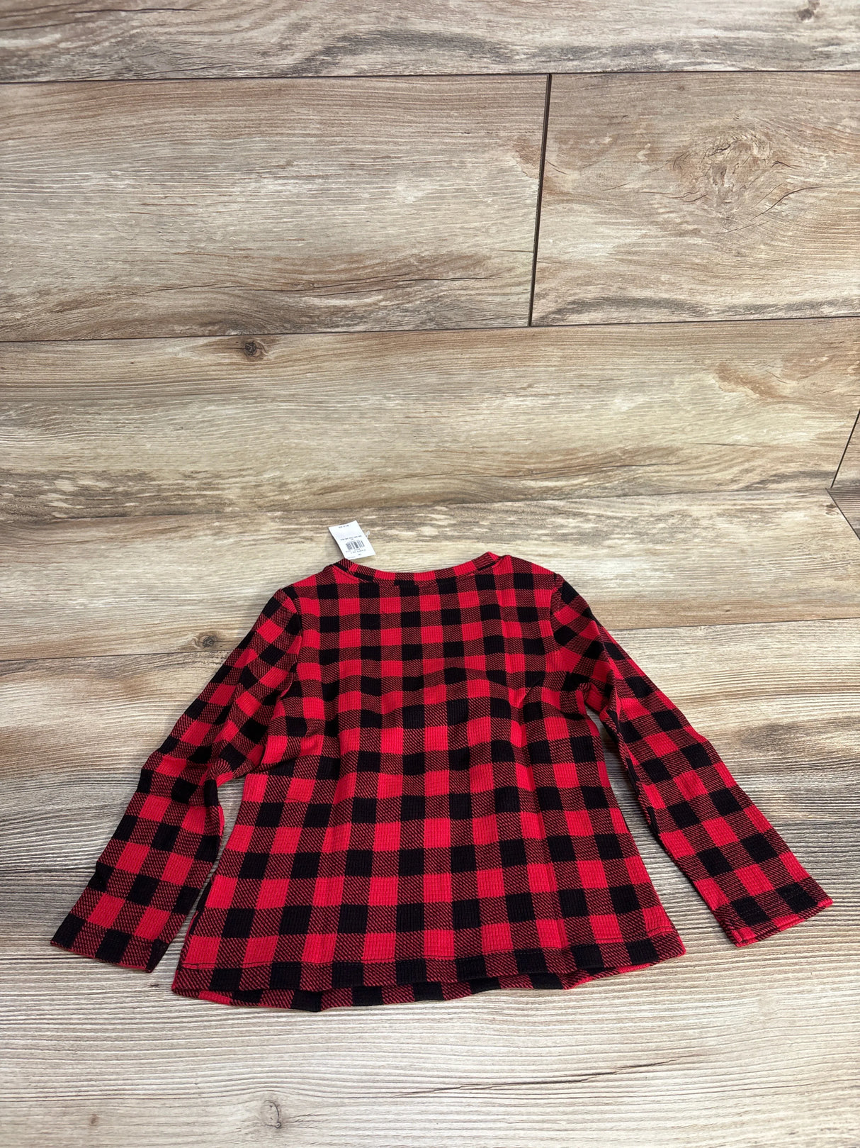 Red and black plaid long sleeve shirt on wood floor