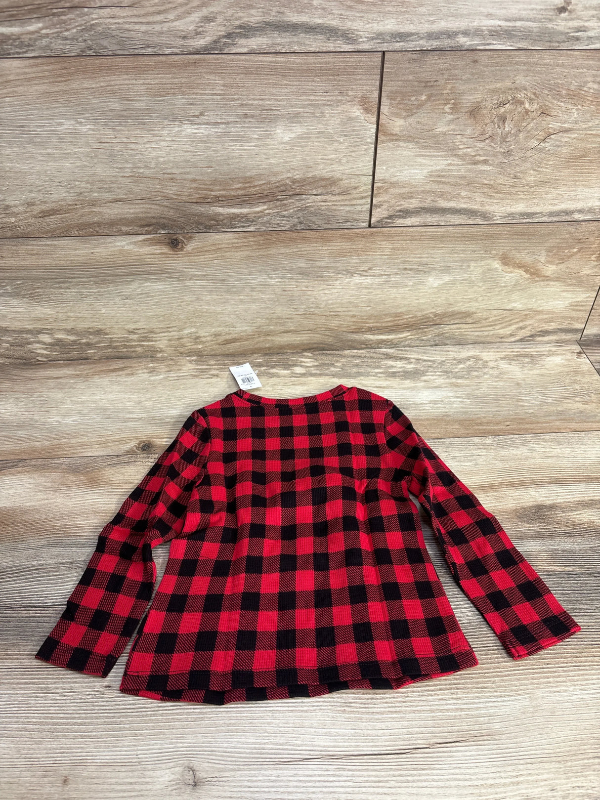 Red and black plaid long sleeve shirt on wood floor