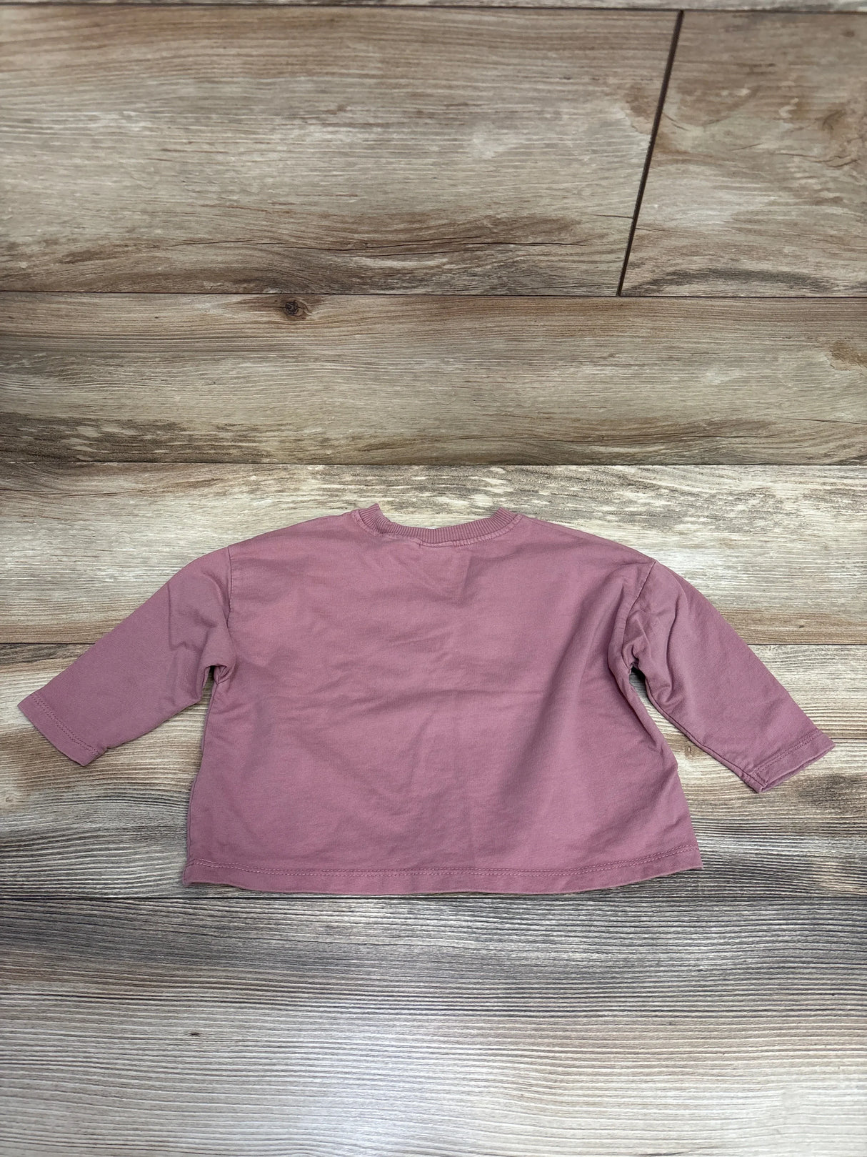 Mauve long sleeve baby shirt on wood background, gently used kids clothing resale