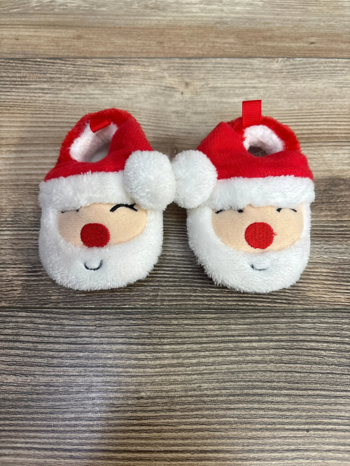 Adorable Santa baby booties with red hat, white beard, and red nose, perfect for holiday photos and cozy comfort.
