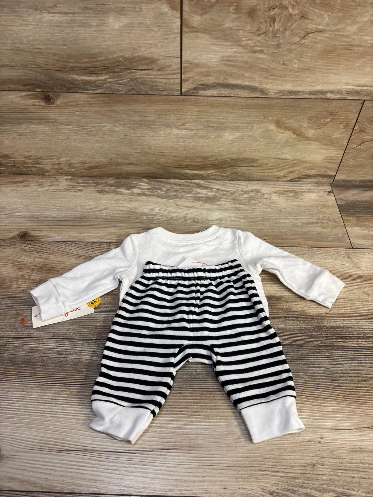 Flat lay of newborn white long-sleeve top and black-and-white striped joggers with elastic waist on wood background