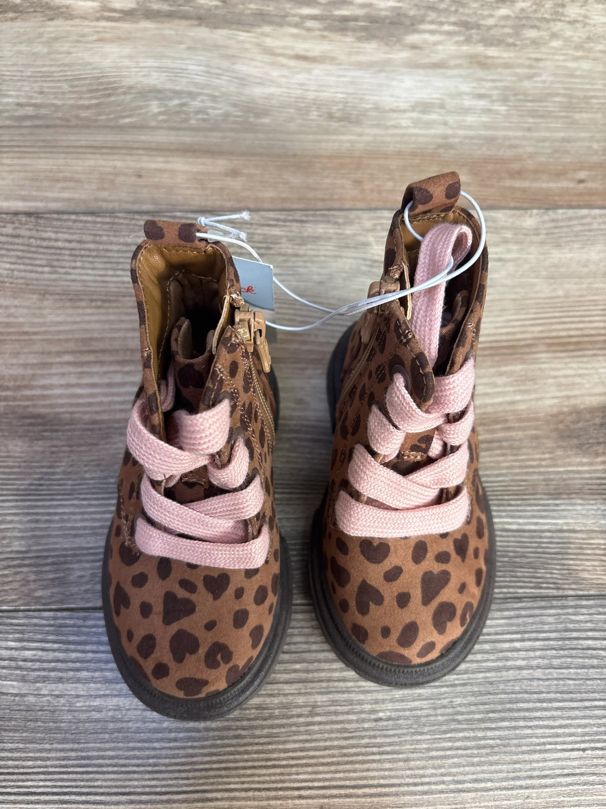 Brown leopard print kids boots with pink laces on wooden floor