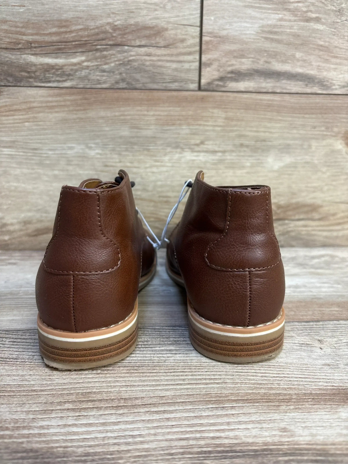 Back view of Cat & Jack Filip toddler boots in brown, size 3Y showing stacked rubber heel and smooth leather upper on wood floor