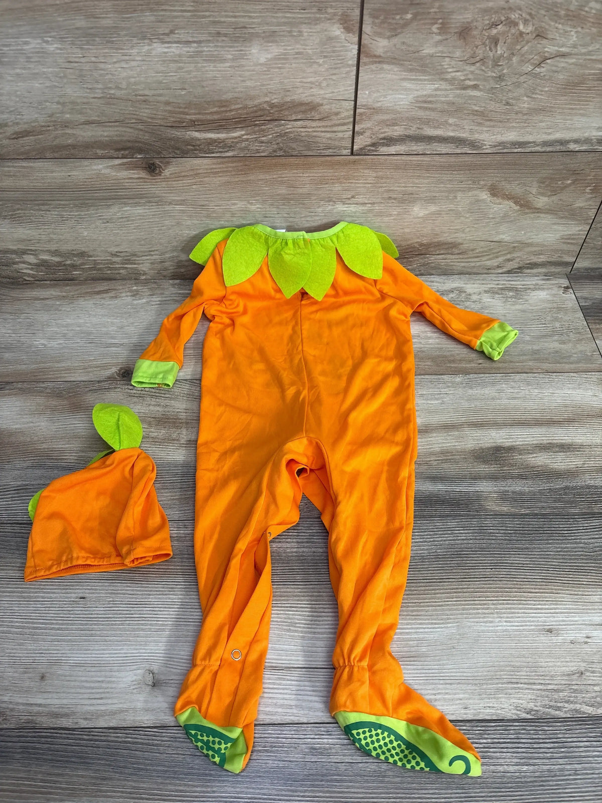 Orange pumpkin-themed baby onesie with green leaf accents and matching hat, perfect for Halloween or fall.