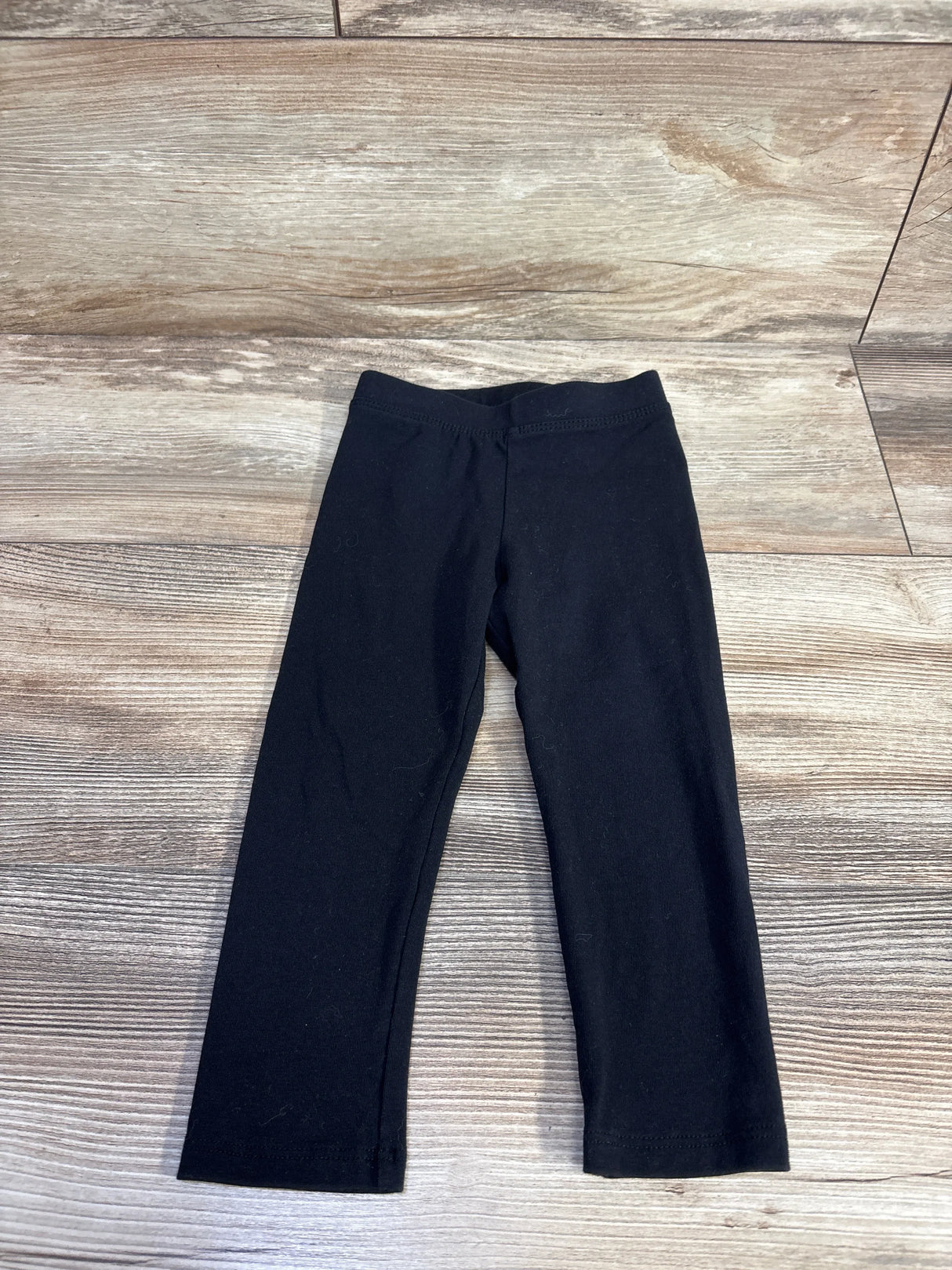 Front flat lay of Amazon Essentials toddler leggings size 2T showing elastic waistband and straight legs on light wood floor