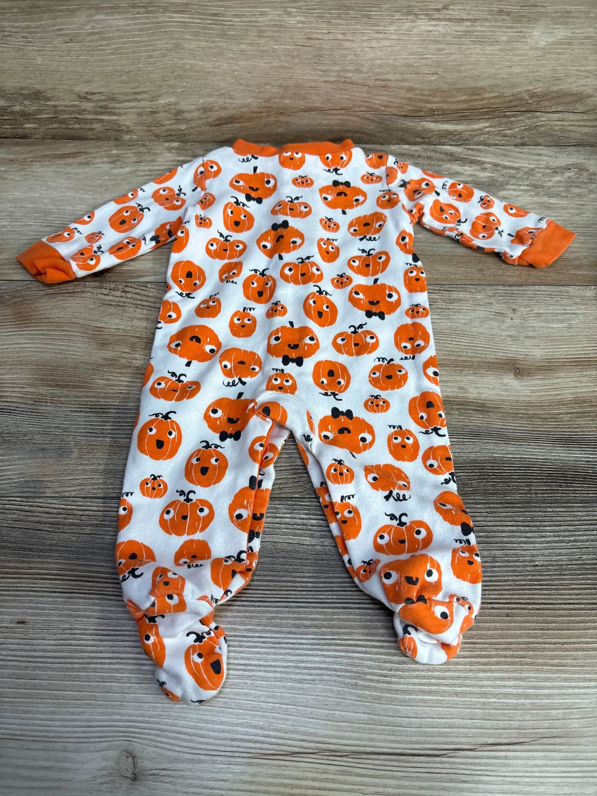 Front view of Baby Starters pumpkin print sleeper with long sleeves and enclosed feet in white on wood grain