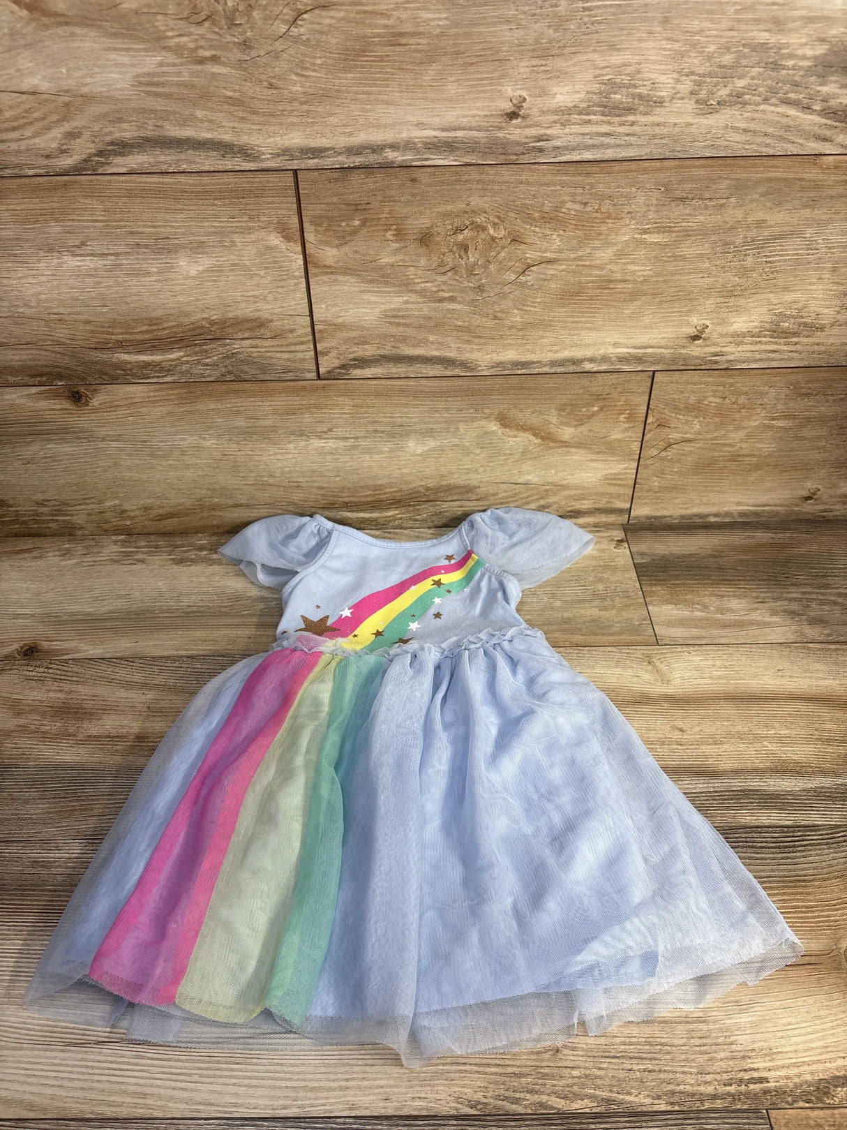 Flat lay of Cat & Jack blue tulle girls' dress (4T) showcasing rainbow tulle panels and star print on wood floor