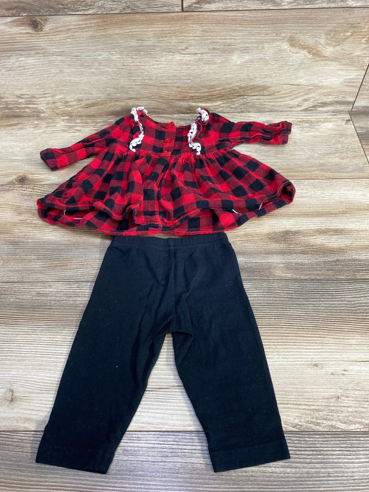 Red and black plaid baby dress with black leggings on wood floor