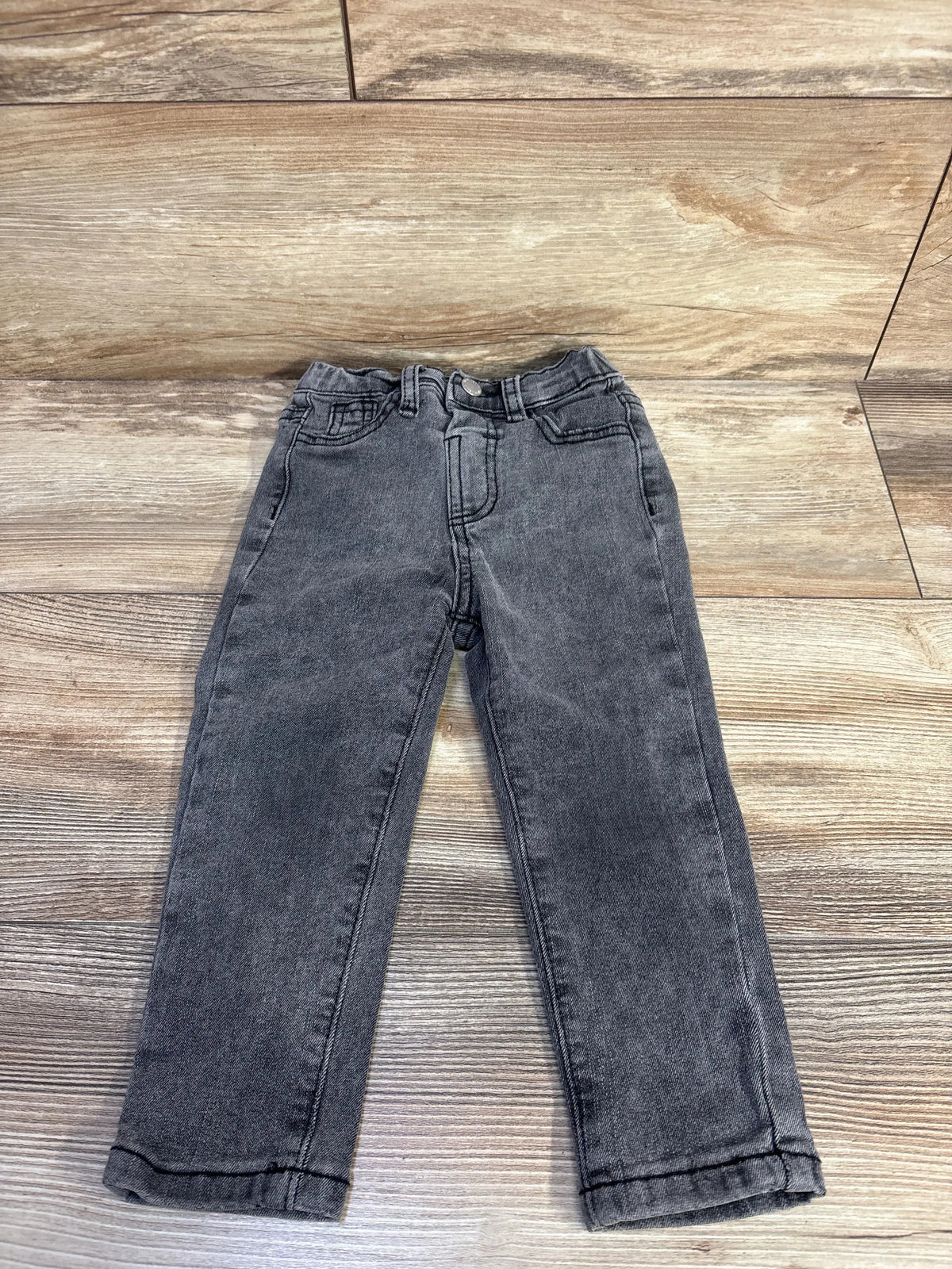 Flat-lay of grey toddler jeans size 2-3T showing straight legs, elasticized waist and front pockets on wood floor background
