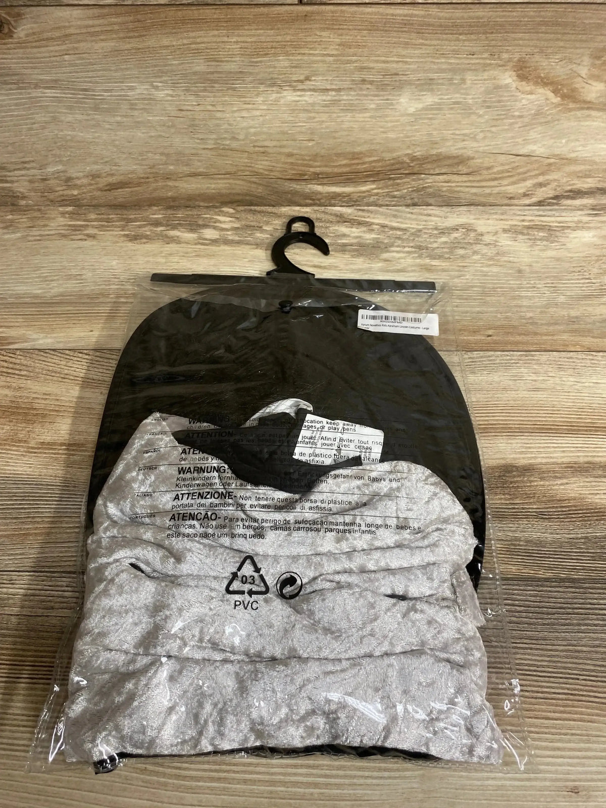 Front view of Rubie’s Abraham Lincoln costume size 10-12 with folded shirt and black hat in clear packaging on wood floor