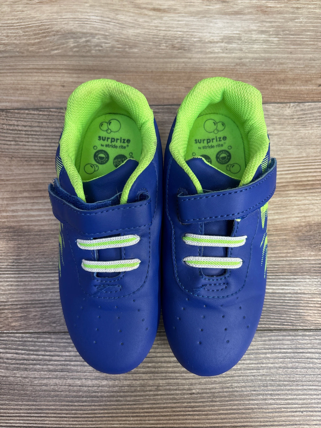 Pair of blue and green Stride Rite Surprize kids shoes with velcro straps on wooden floor