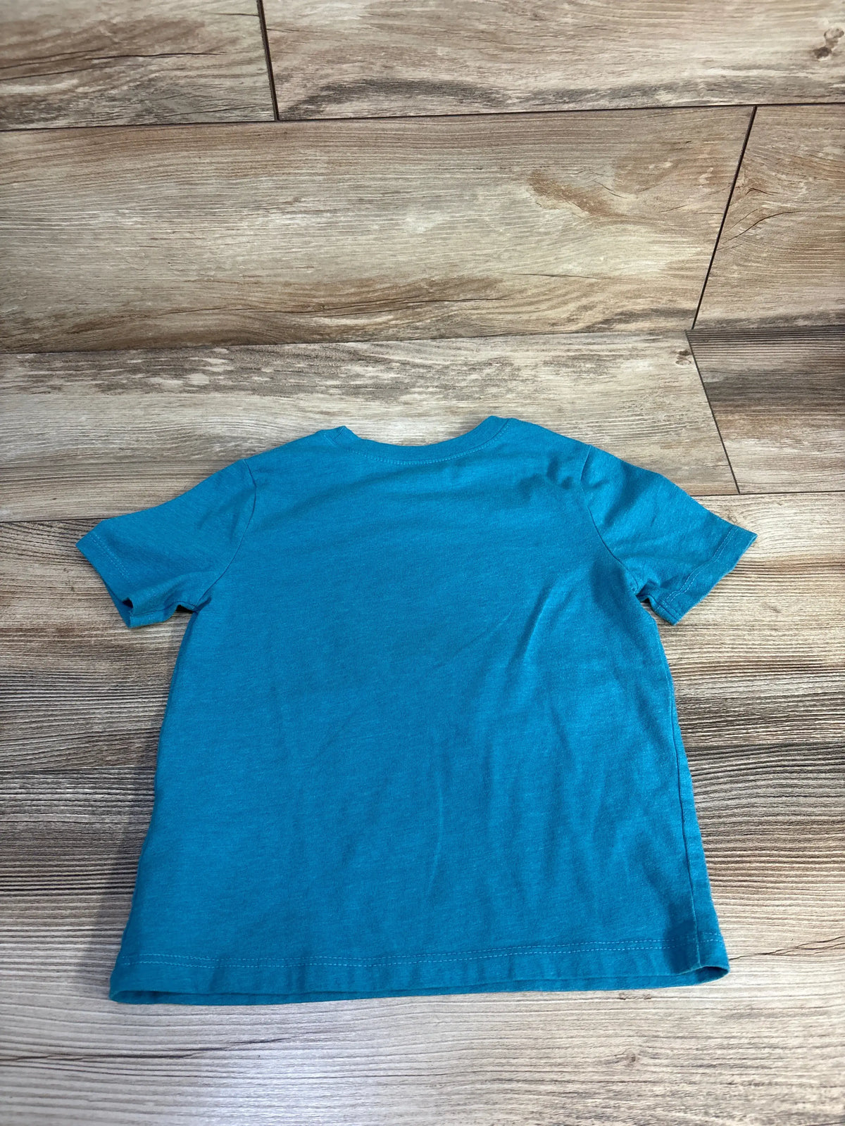 Back view of Old Navy PAW Patrol shirt showcasing blue short sleeves and crew neckline on a wood floor