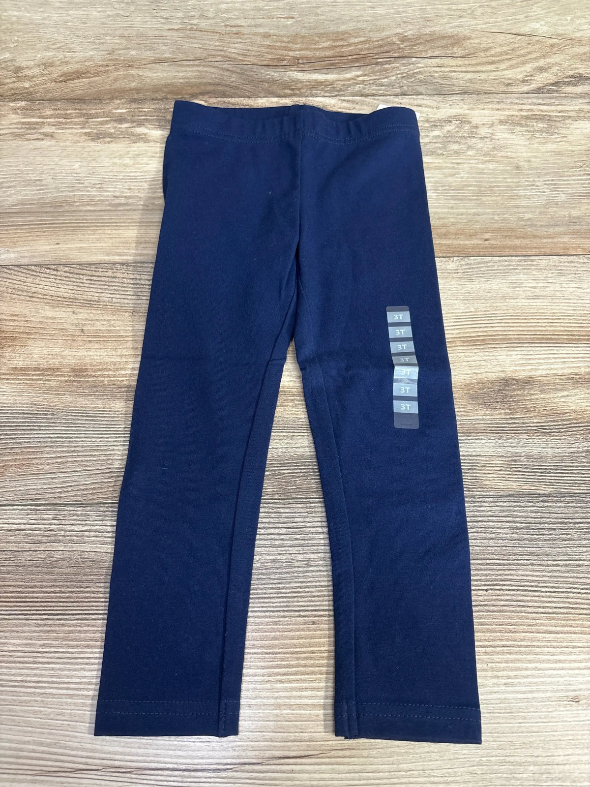 Navy blue toddler leggings size 3T on wood background, children's clothing resale