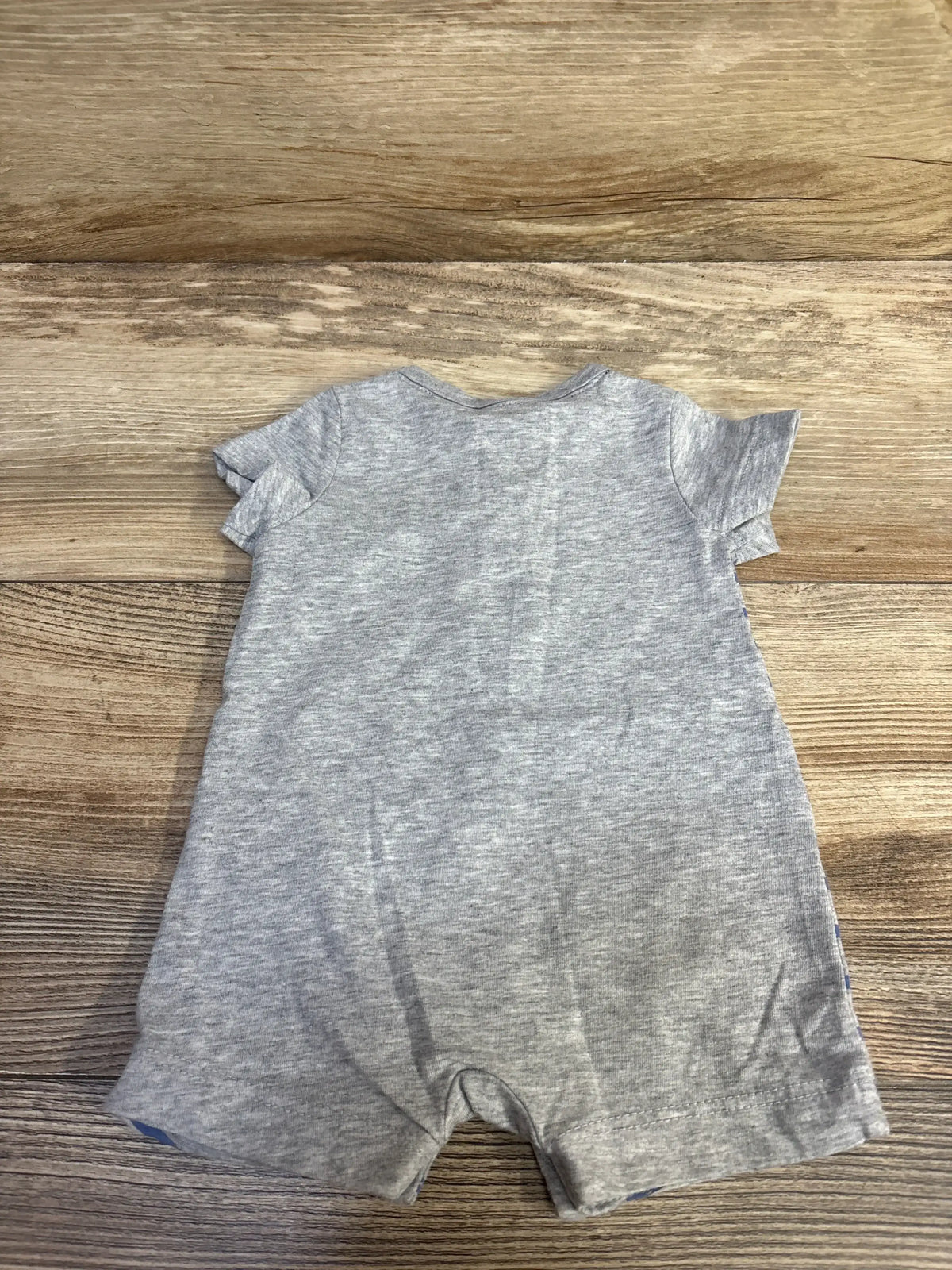 Flat-lay of grey Carter’s Henley romper, newborn size, showing short sleeves and snap closures at legs on wood background