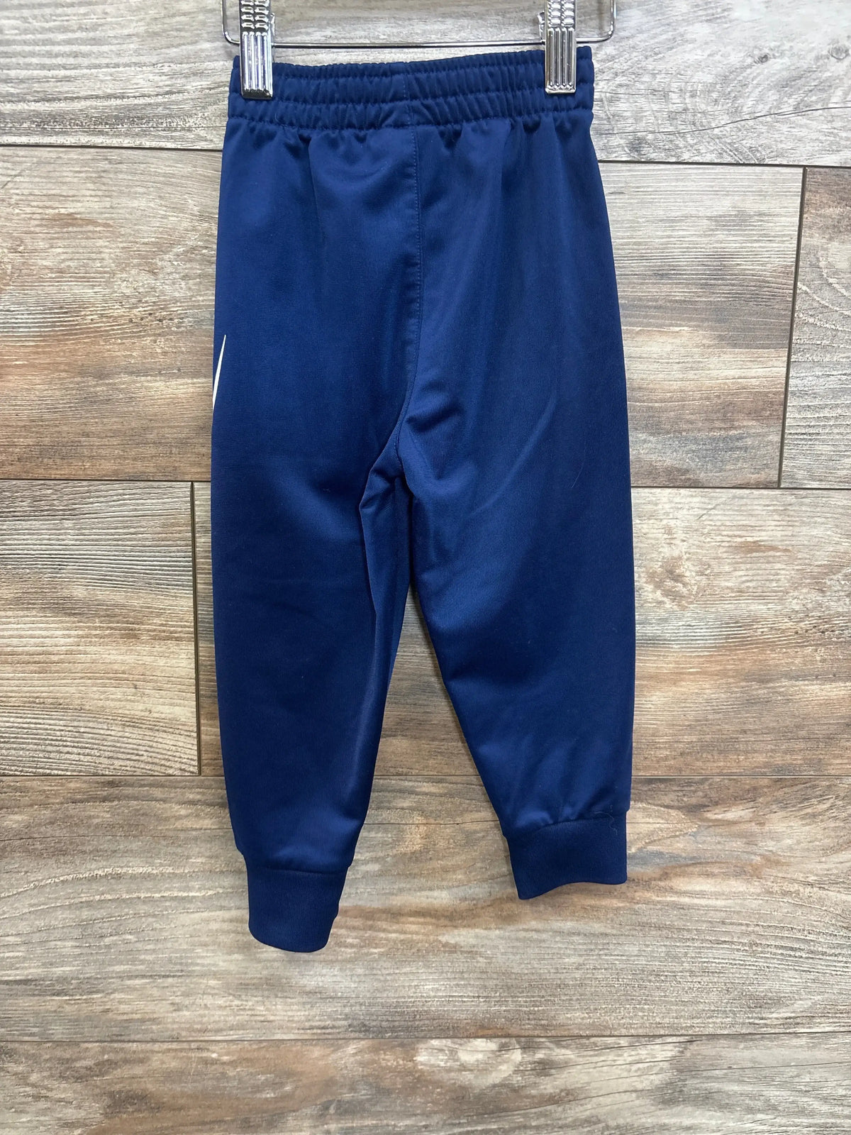 Navy blue toddler jogger pants with elastic waistband on wooden background