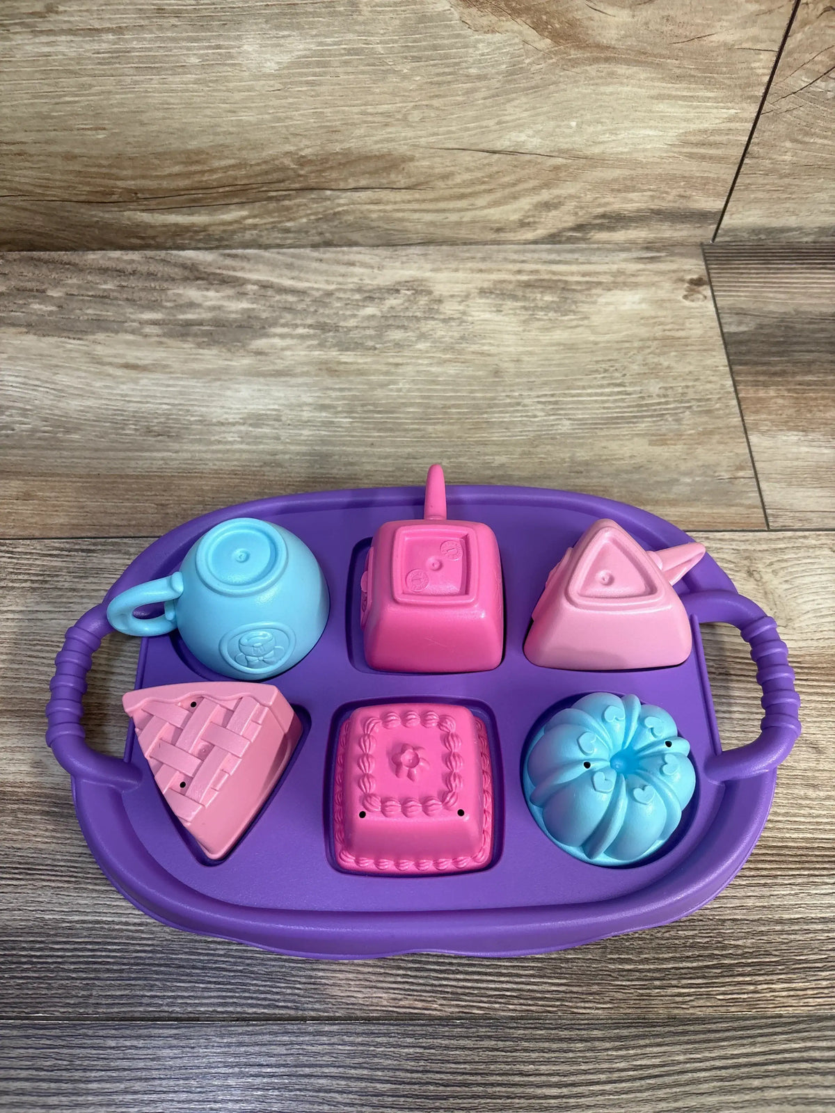 Overhead view of Green Toys Disney Minnie Mouse Tea Party Set showcasing purple numbered tray, three shaped cups, and desserts
