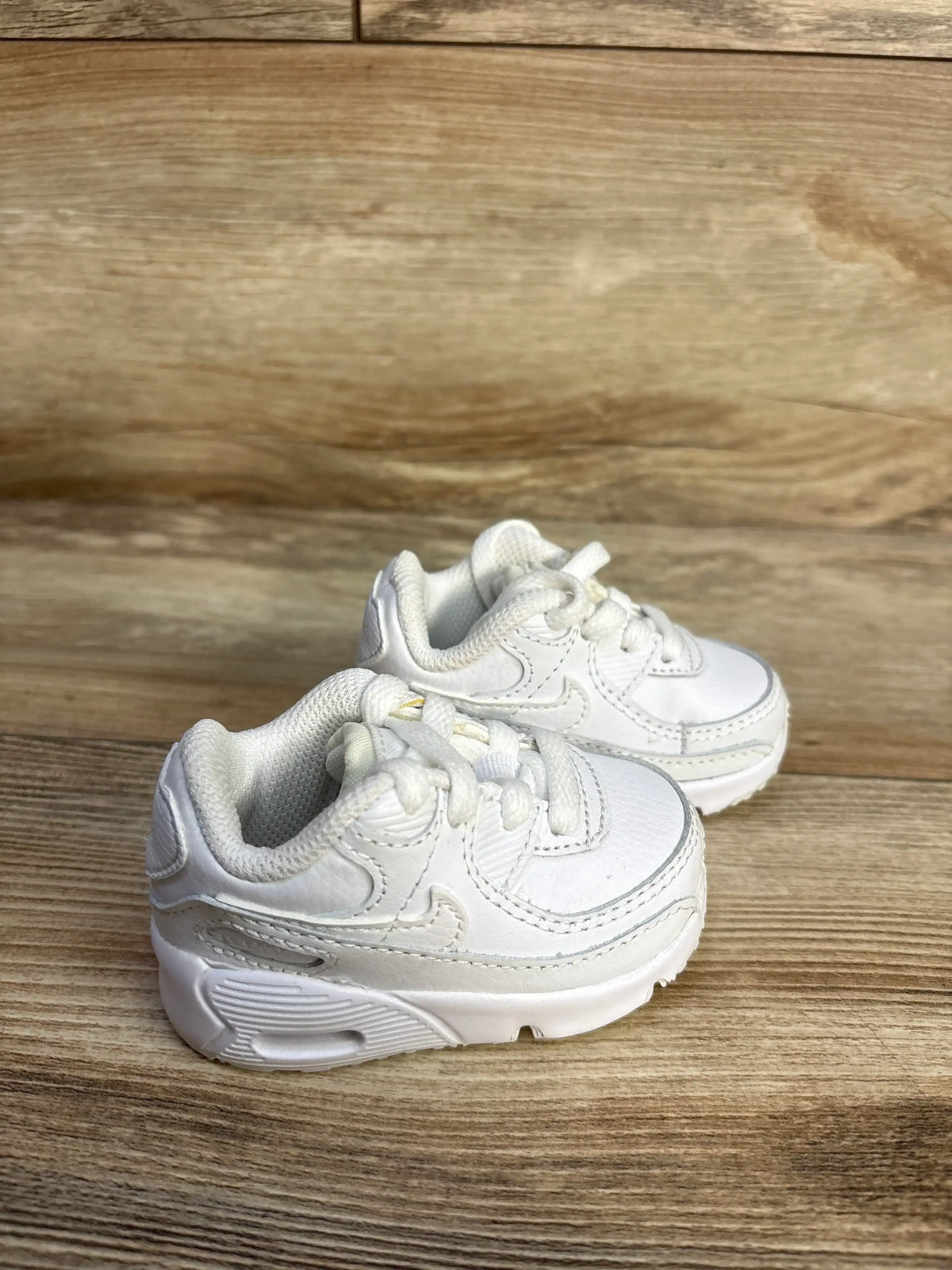 Pair of white Me n Mommy To Be Nike Air Max 90 TD sneakers on a wooden surface.