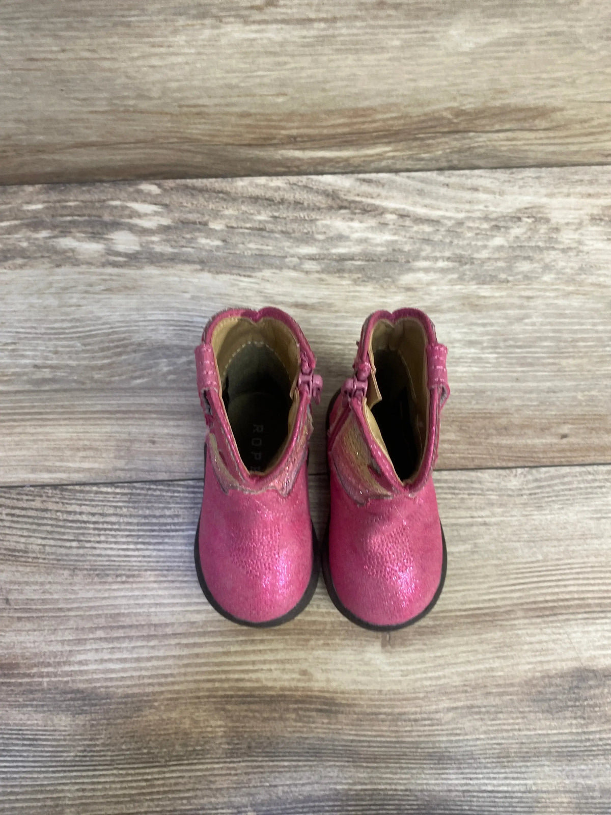 Top view of Roper Infant Glitter Cowbabies boots showcasing purple glitter vamp and brown shaft on wood background
