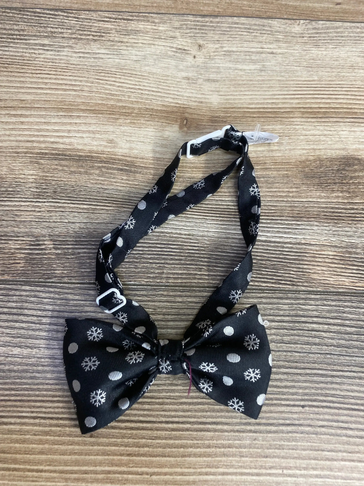 Black kids bow tie with snowflake and polka dot pattern on wood background