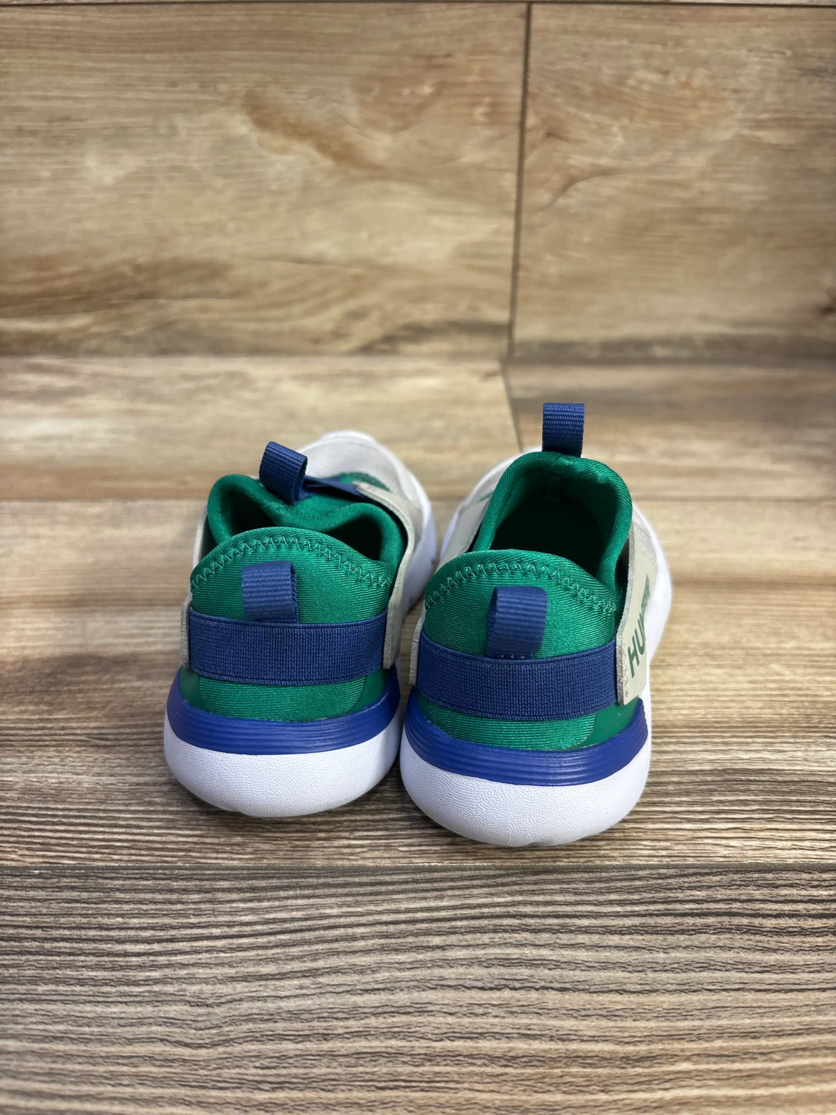 Rear view of Hunter Gemini sneakers showcasing green and blue heel bands with white soles on a wood floor