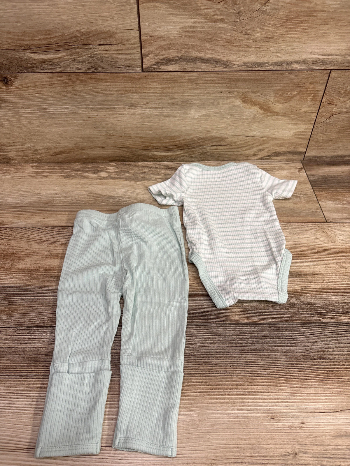 Top view of Little Me mint green striped bodysuit and pants set in size 3 months, laid flat on a wood-look floor