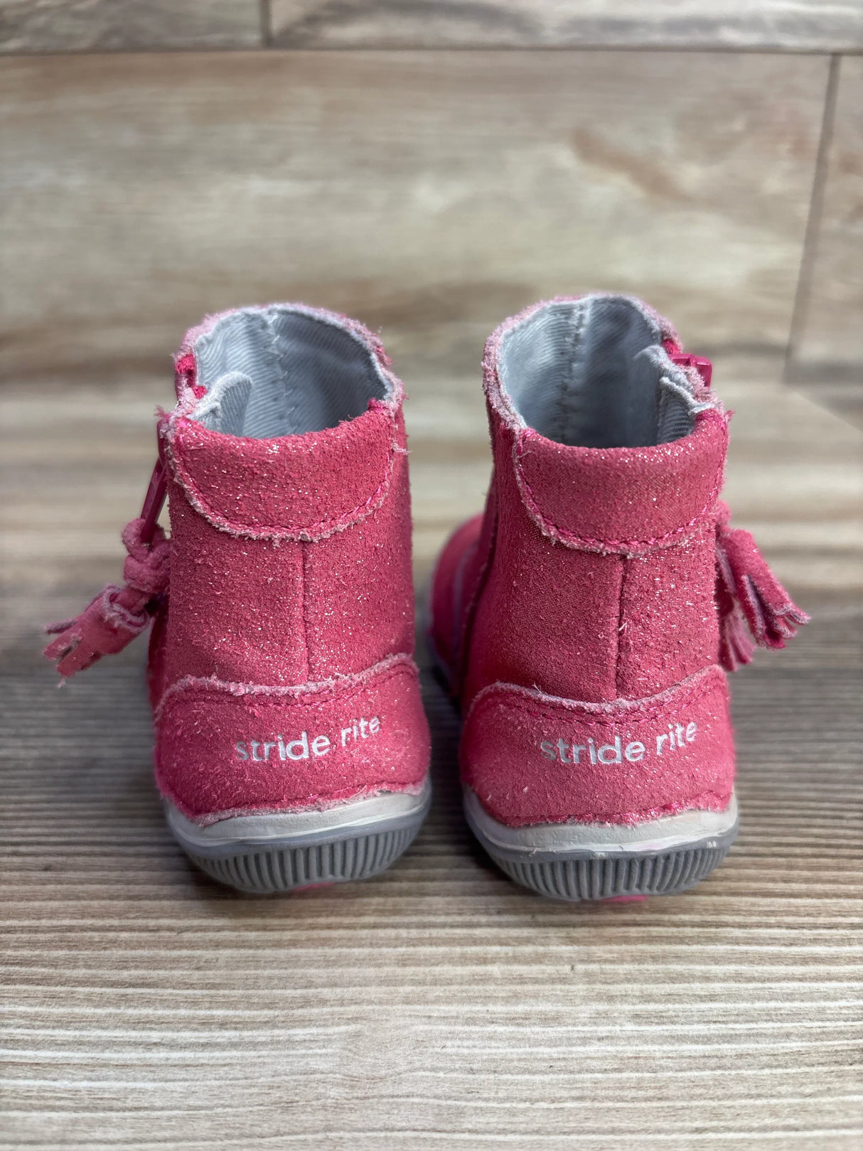Back view of pink toddler Stride Rite boots with tassels on wooden floor