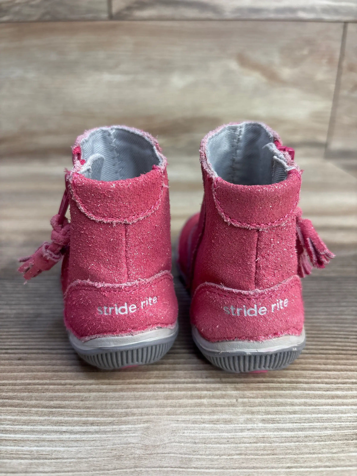 Back view of pink toddler Stride Rite boots with tassels on wooden floor