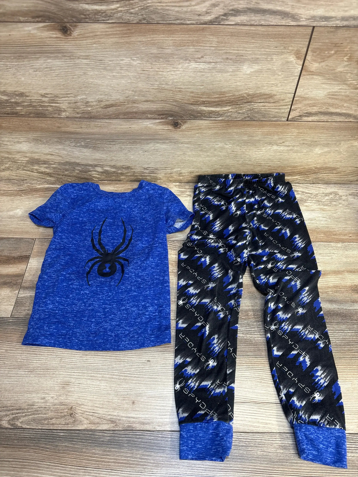 Blue spider graphic kids shirt with matching patterned pants set on wood background