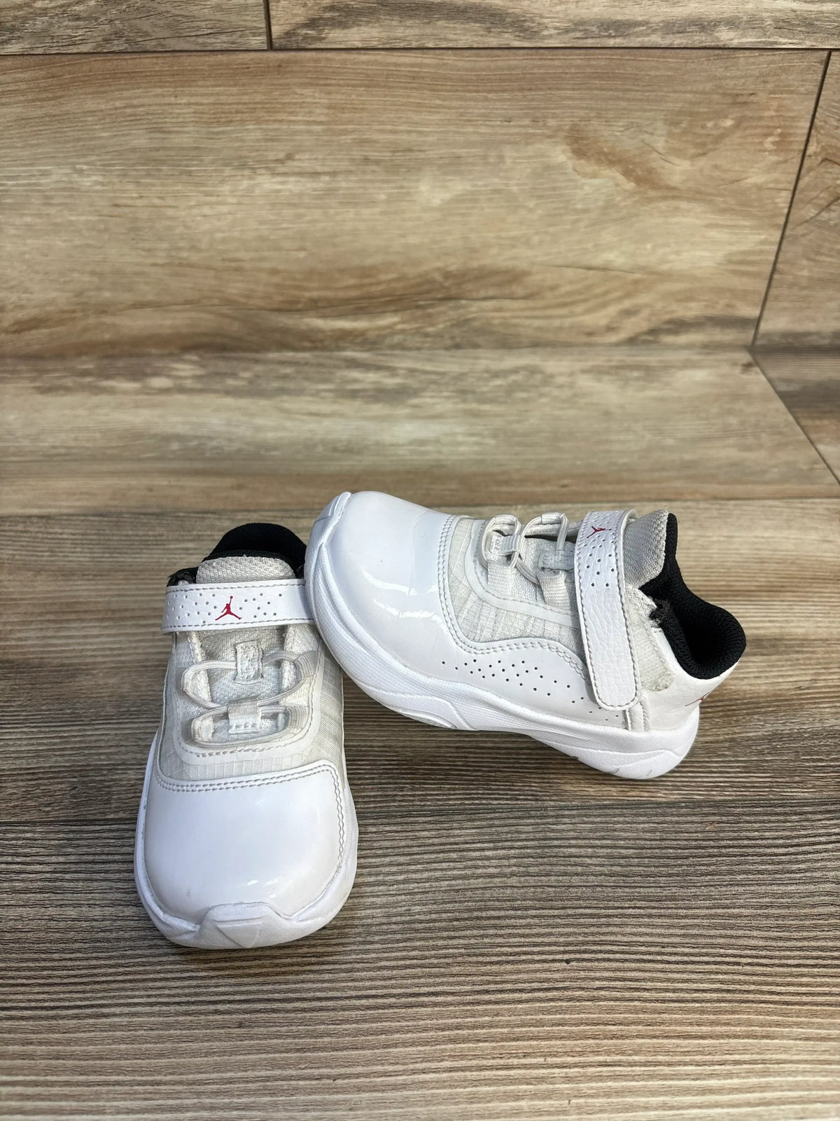 White toddler sneakers with velcro straps on wood floor, gently used kids shoes