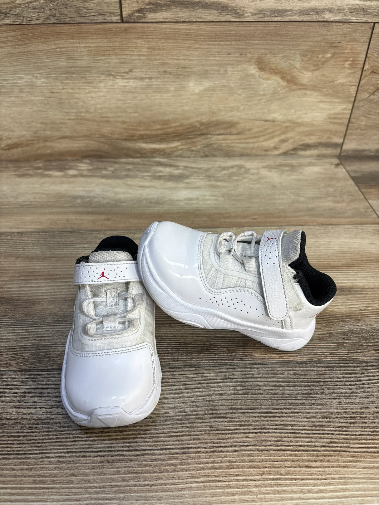 White toddler sneakers with velcro straps on wood floor, gently used kids shoes