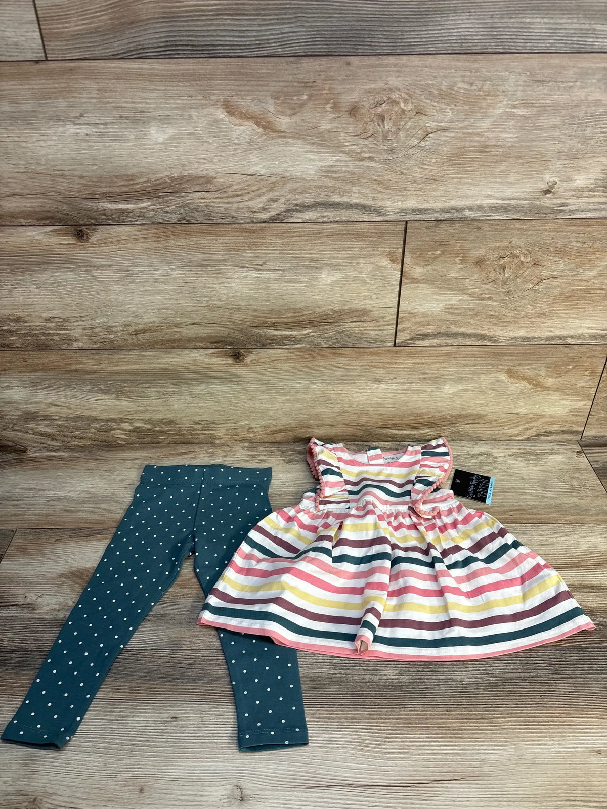 Girls' striped dress with ruffle sleeves and teal polka dot leggings on wood background