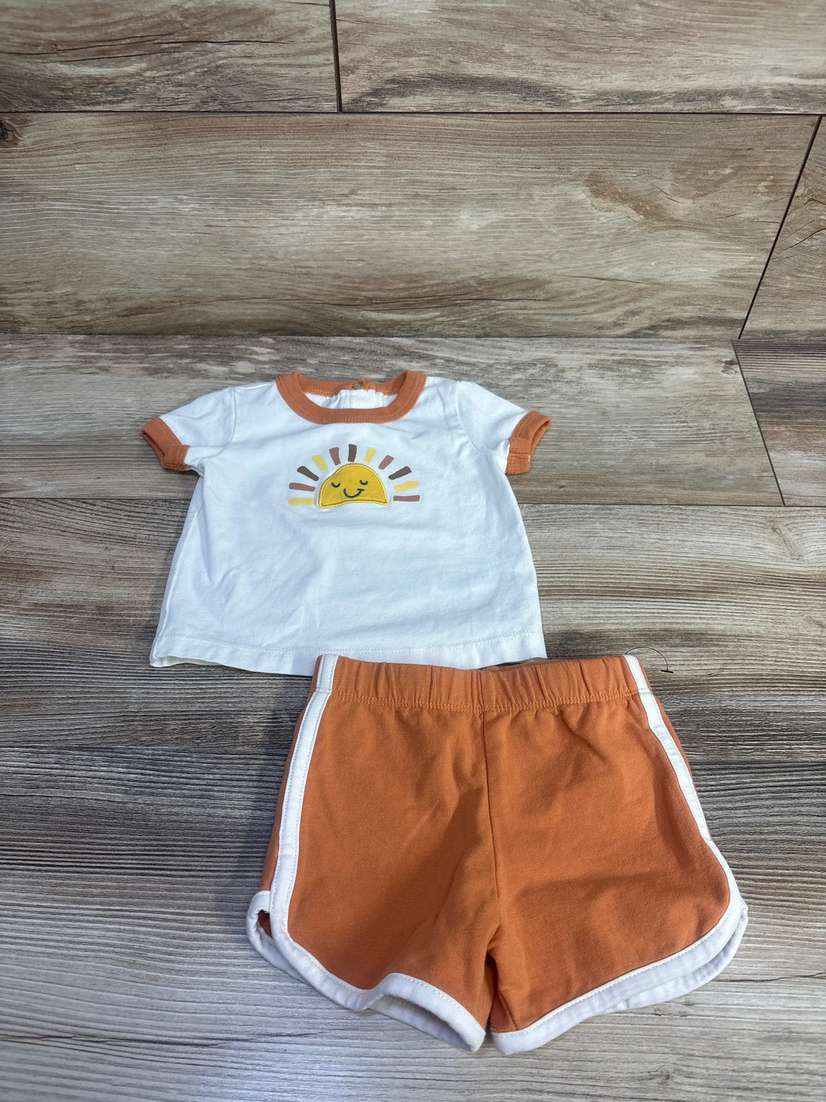 Front view of Focus Sun Shirt and Shorts Set showcasing a sun graphic, contrast trim, and side stripes on a wood floor