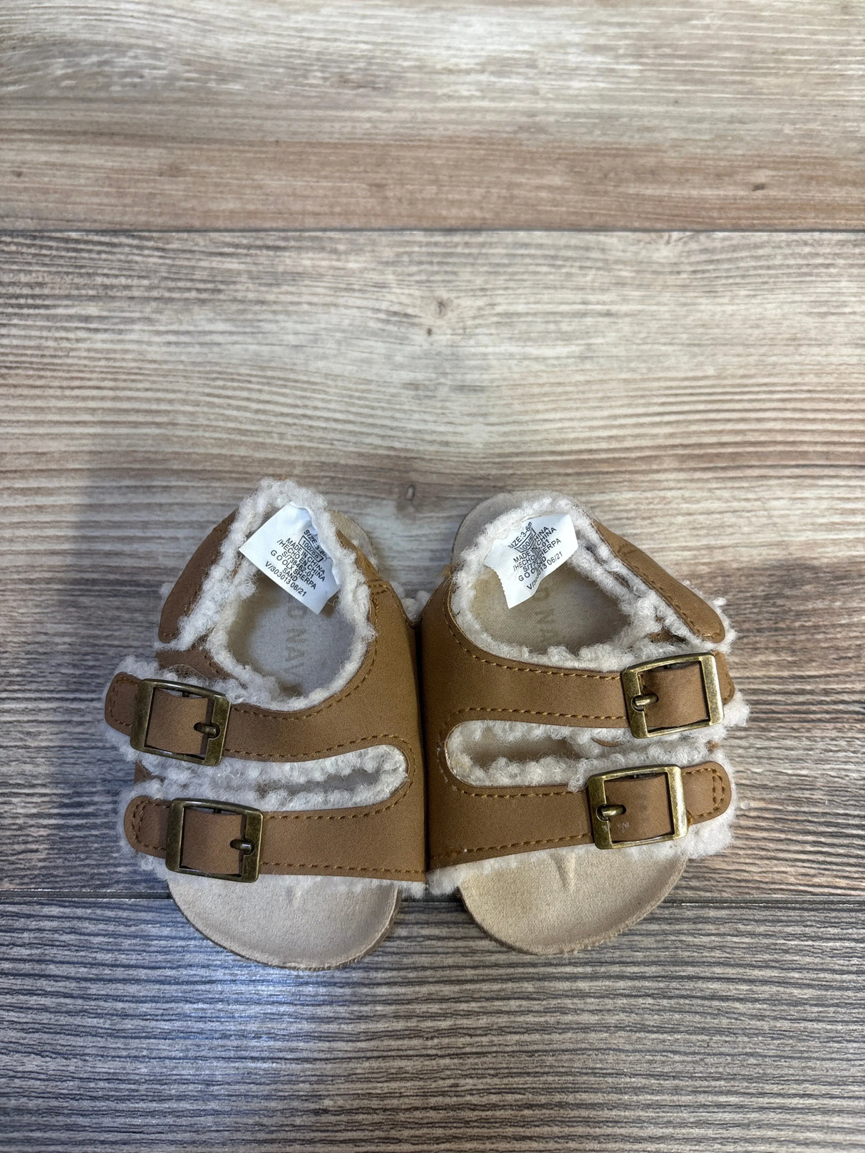 Top view of Old Navy sherpa-lined toddler strap sandals size 1/2C showing faux-shearling lining and twin buckles on wood background