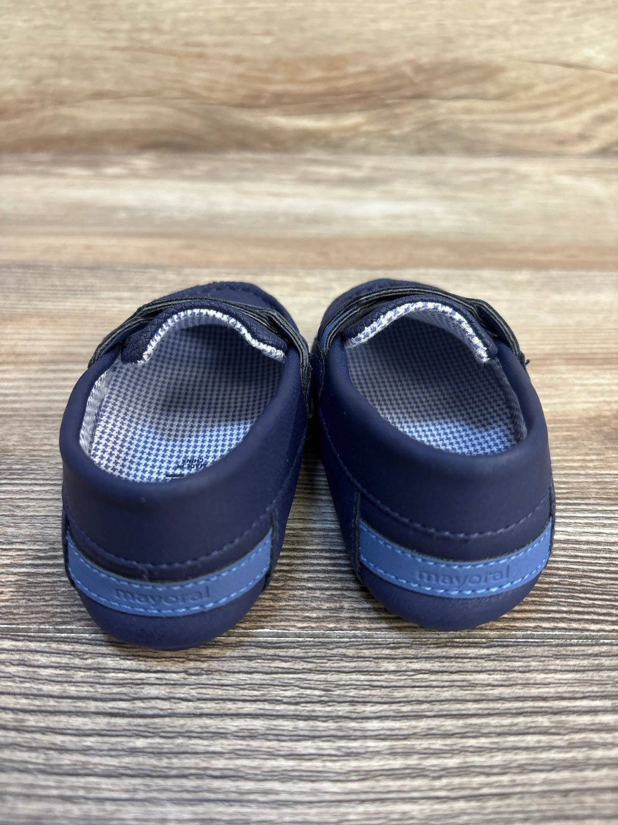Navy blue Mayoral baby shoes with checkered lining on a wood surface