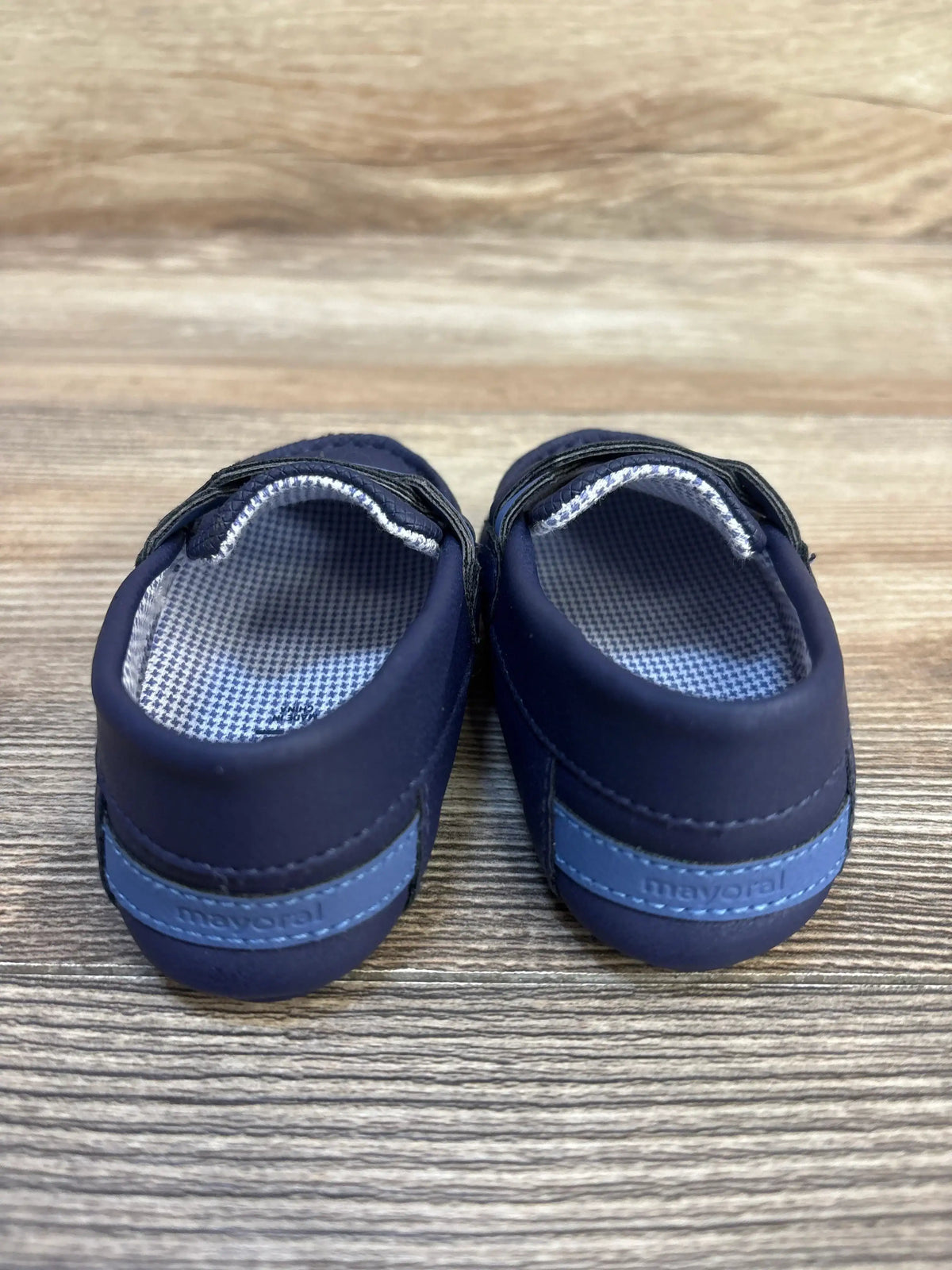 Navy blue Mayoral baby shoes with checkered lining on a wood surface