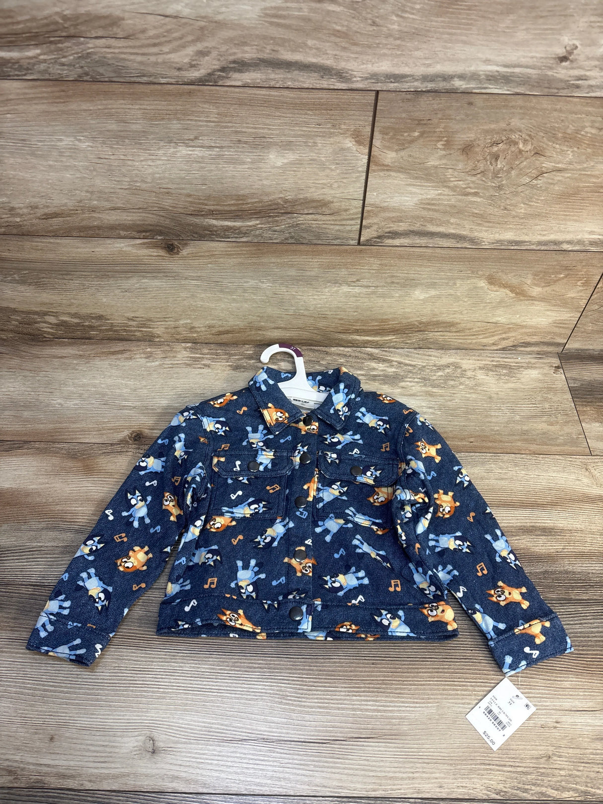 Blue toddler jacket with cartoon dog and music note print, long sleeves, laid on wood floor