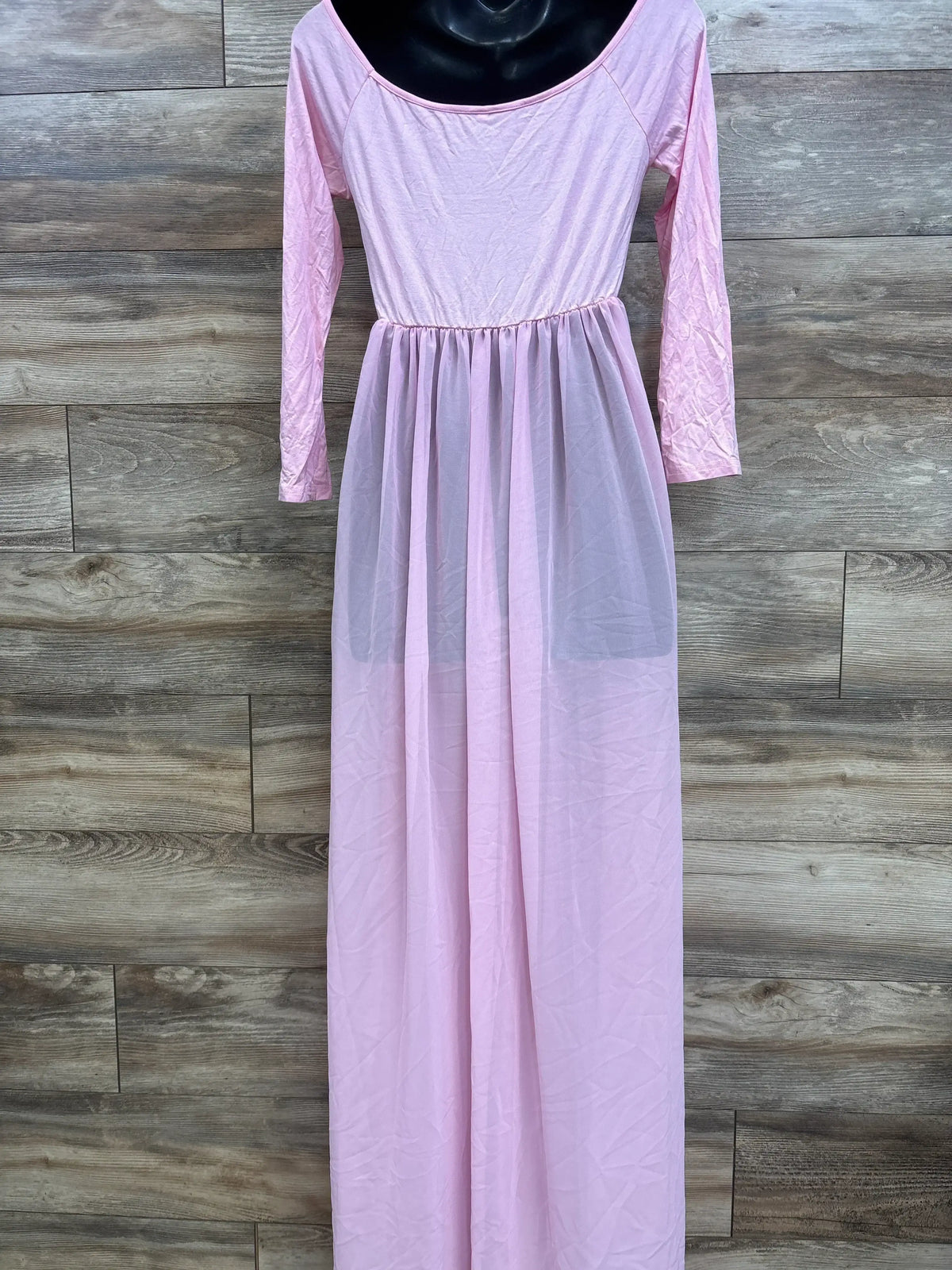 Front view of Odeerbi maternity pink off-shoulder maxi dress with long sleeves and sheer skirt overlay on wood background